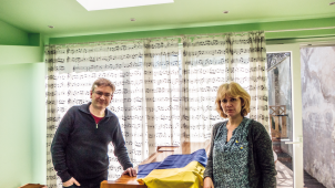 Alexei et Nataliya posent fièrement aux côtés d’un drapeau ukrainien qui enveloppe un piano.