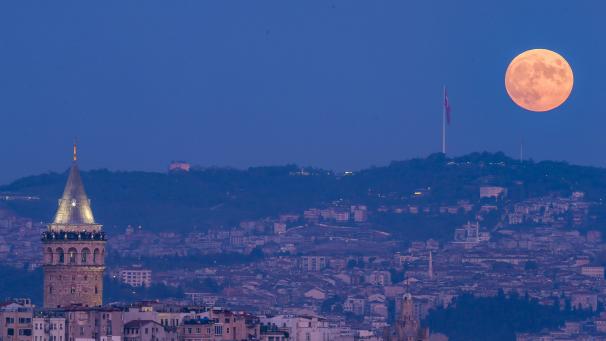 La pleine lune se lève derrière la tour de Galata à Istanbul, en Turquie.