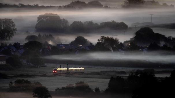 Un train régional passe devant des champs couverts de brouillard à Wehrheim près de Francfort, en Allemagne.