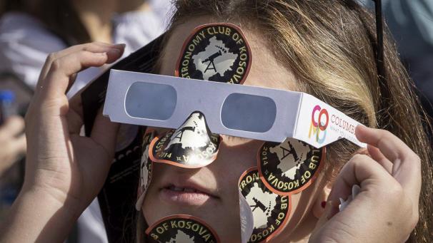 Une fille portant des lunettes de soleil observe une éclipse solaire partielle dans la capitale du Kosovo, Pristina.