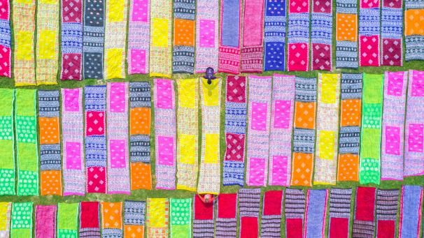 Au Bangladesh, les travailleurs ont étalé des tissus colorés et des saris sur un champ pour sécher sous le soleil.