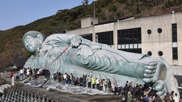Environ 200 prêtres bouddhistes et croyants nettoient une statue de Bouddha couché pendant l'événement susuharai pour enlever la poussière au temple Nanzoin dans la ville de Sasaguri, Fukuoka, dans l'ouest du Japon et la région insulaire de Kyusyu, le 26 décembre 2022.