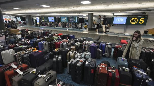 Une femme cherche ses bagages à l'aéroport international de Vancouver après une tempête de neige qui a paralysé les opérations, entraînant des annulations et des retards importants, à Richmond, en Colombie-Britannique, le mardi 20 décembre 2022.