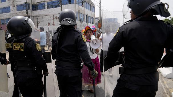 Une manifestante anti-gouvernemental défie la police entourant l'Université San Marcos à Lima, au Pérou.