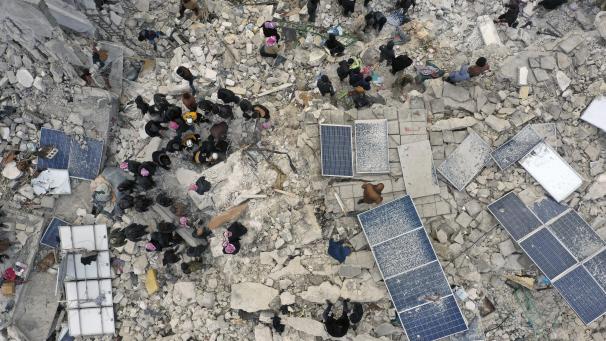 Des employés de la protection civile et des habitants fouillent les décombres de bâtiments effondrés dans la ville de Harem, près de la frontière turque, province d'Idlib en Syrie.