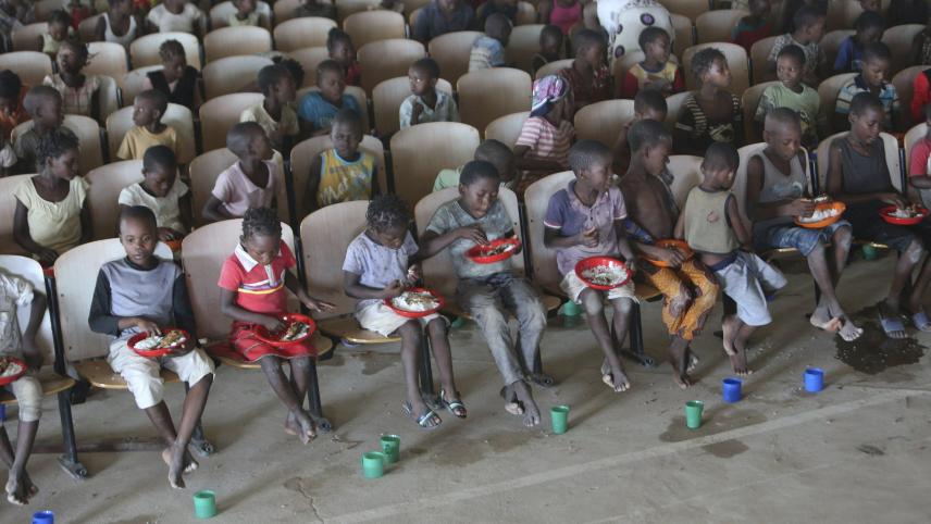 Au Mozambique, des enfants sont sagement assis sur des bancs après avoir reçu de la nourriture et de l’eau potable dans un refuge temporaire de Pemba.