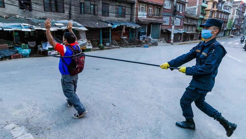 Un policier maintient une distance de sécurité avec un homme qui défie les règles de lockdown, au Népal.