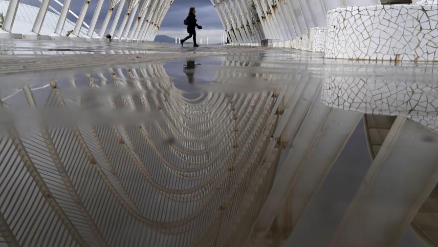 Une femme marche sur une passerelle qui mène au complexe olympique d’Athènes.