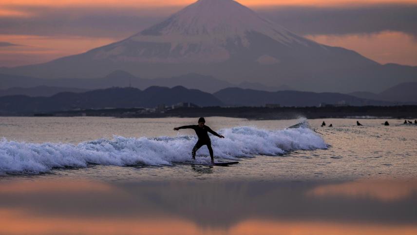 Un surfeur sur une vague devant le mont Fuji au Japon.
