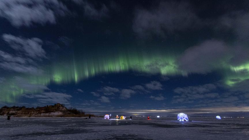 Les aurores boréales illuminent le ciel au-dessus de pêcheurs sur glace dans le golfe de Finlande.