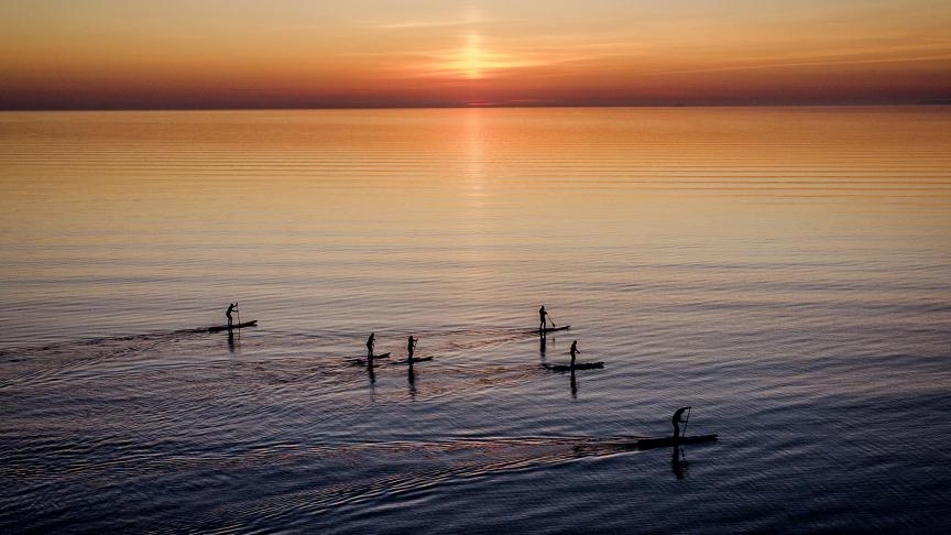 Dans la mer Baltique, des personnes faisant du paddle profitent du lever de soleil.