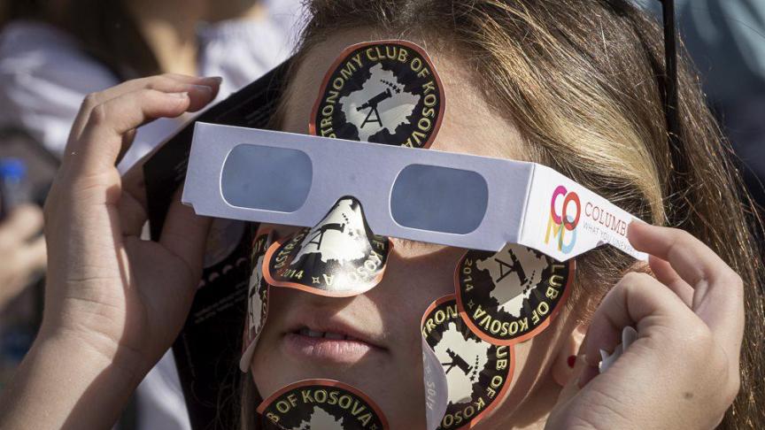 Une fille portant des lunettes de soleil observe une éclipse solaire partielle dans la capitale du Kosovo, Pristina.